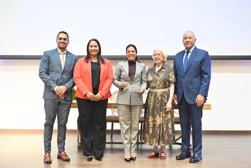 Subdirectora general del IDAC, Paola Aimée Plá Puello, recibiendo el reconocimiento de la DIGEIG de manos de Milagros Ortiz Bosch.
